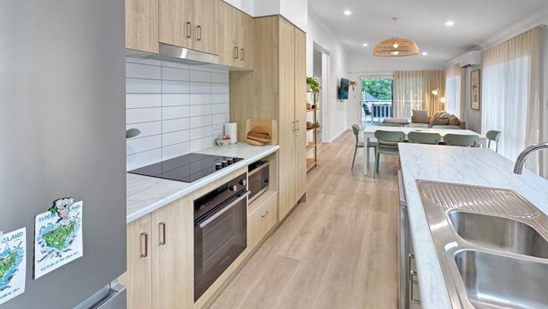 Een moderne keuken met houten kastjes, een inbouwoven en een roestvrijstalen spoelbak.