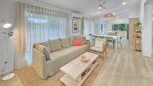 Een moderne woonkamer met een bank, salontafel en een eethoek.