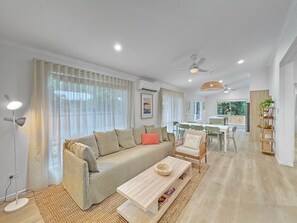 Ein modernes Wohnzimmer mit Sofa, Couchtisch und Essbereich.