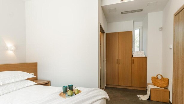 A hotel room with a bed, bedside table, and a wardrobe. - Chic Family Villa With Pool in Syvota (Igoumenitsa)
