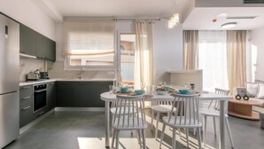 A modern kitchen with dark cabinets, a white dining table, and chairs. - Chic Family Villa With Pool in Syvota (Igoumenitsa)