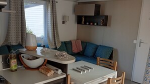Una cucina compatta con angolo ristoro, divano e finestra con tende a motivi.