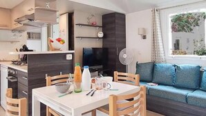 Un ambiente compatto con angolo cottura, zona pranzo e divano.