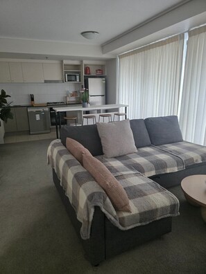 A modern living room with a sofa, a dining area, and a kitchen. - River and city view 1 Bedroom apartment (Brisbane City)
