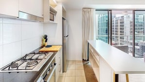 Una cocina moderna con estufa a gas, un refrigerador y una ventana con vistas a la ciudad.