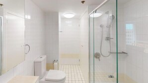 A modern bathroom with a glass shower enclosure, a toilet, and a bathtub. - River and city view 1 Bedroom apartment (Brisbane City)