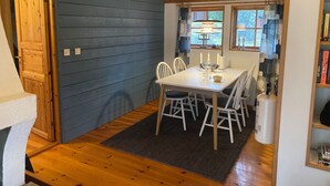 Un comedor con una mesa y sillas de madera, un reloj en la pared y una estantería.