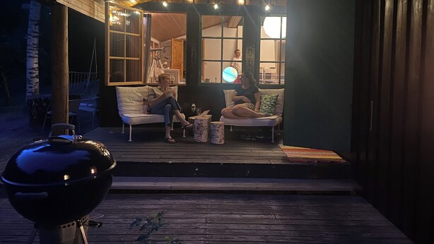 Un espacio al aire libre con porche cubierto, una parrilla y vistas hacia la casa.