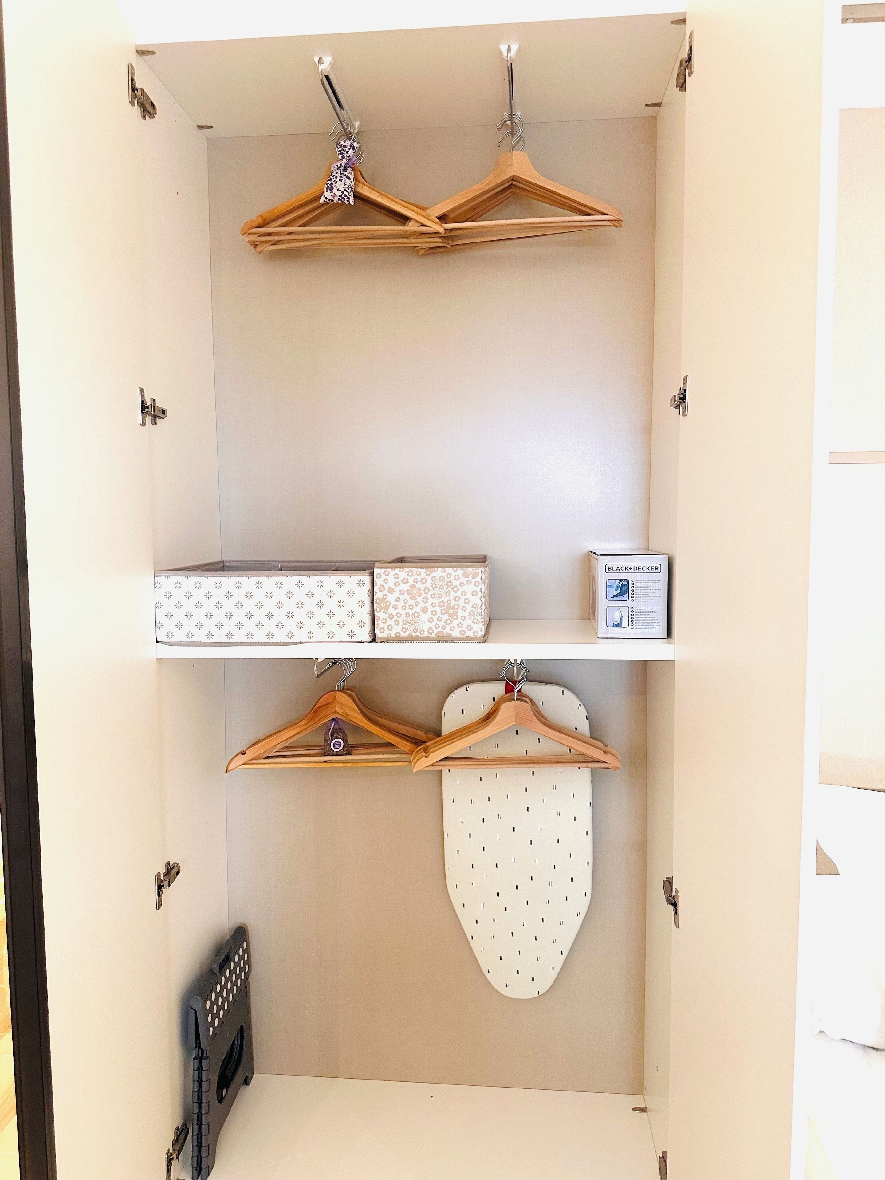 A closet with wooden hangers, patterned boxes, and a white coat hanging on a wall.
