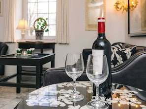 Una botella de vino sobre una mesa con dos copas, una lámpara, una planta y un sofá en una habitación.