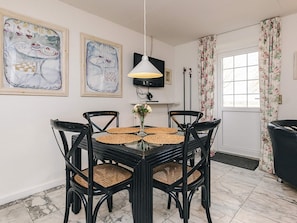 A dining area with a round table, four chairs, a vase with flowers, and two framed artworks on the wall. - 4 Person Holiday Home in Brovst (Brovst)