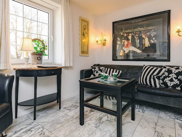 A living room with a sofa, two side tables, a lamp, a potted plant, and a framed picture on the wall. - 4 Person Holiday Home in Brovst (Brovst)