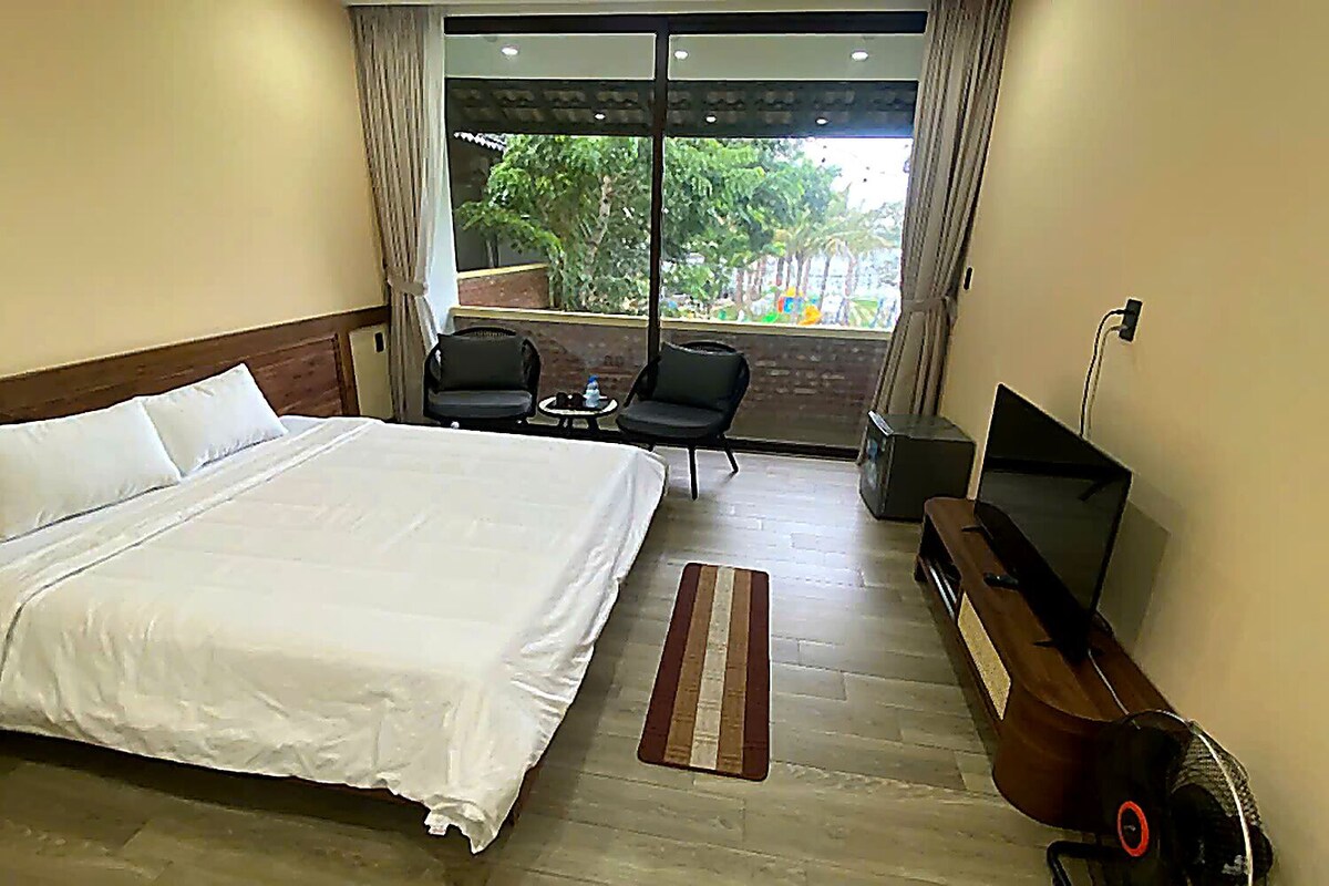 Habitación de hotel con cama, escritorio, silla, una guitarra y televisor.