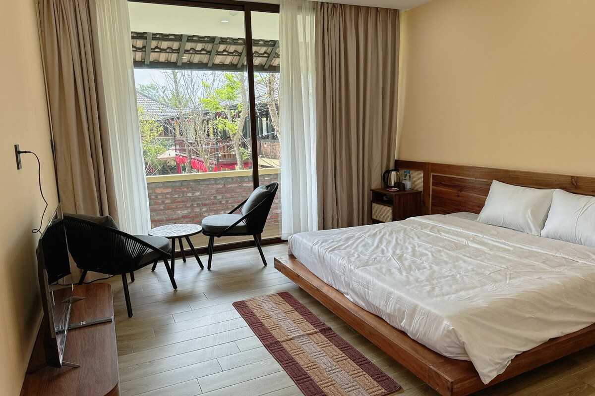 Habitación de hotel con cama, escritorio, silla, una mesita y vistas por la ventana.