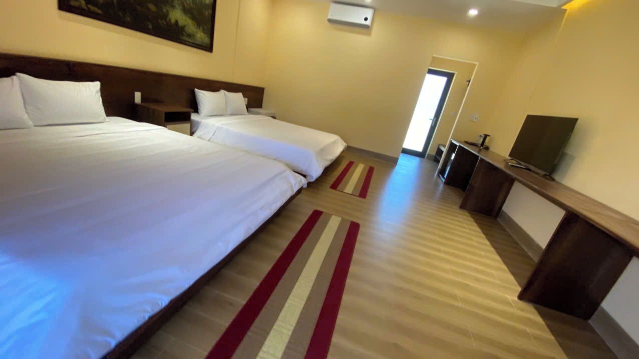 A hotel room with two beds, a TV, and a desk.