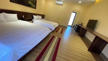 A hotel room with two beds, a TV, and a desk.