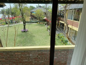 A view of a courtyard with a grassy area, trees, and a building with a tiled roof. - Con Nho RiverHouse Hue (Hue)