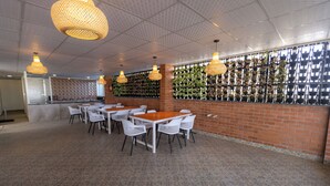 A restaurant with a brick wall, white chairs, and hanging lights. - SUNIQ (Bengaluru)