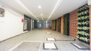 A hallway with a tiled floor, recessed lighting, a fire extinguisher, and a wall with a vertical garden. - SUNIQ (Bengaluru)