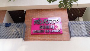 A sign for 'SUNIQ LUXURY CO LIVING' on a brick building. - SUNIQ (Bengaluru)