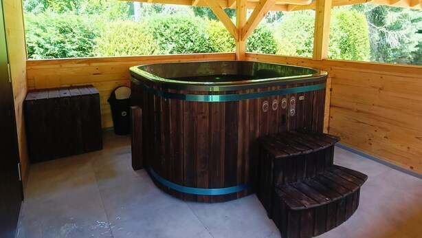 A wooden hot tub with a circular shape and a wooden exterior, surrounded by wooden benches. - Apartment in Lapsze Nizne With Balcony (Lapsze Nizne)