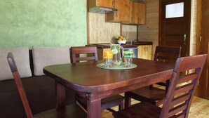 A wooden dining table with chairs, a kitchen area with wooden cabinets, and a green wall. - Apartment in Lapsze Nizne With Balcony (Lapsze Nizne)