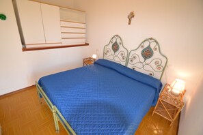 Een slaapkamer met een bed, een nachtkastje, een wandplank en een decoratief kunstwerk.
