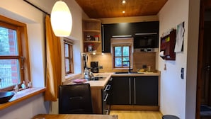 Een moderne keuken met houten kastjes, een zwart aanrecht, een spoelbak en een eethoek met een tafel en stoelen.