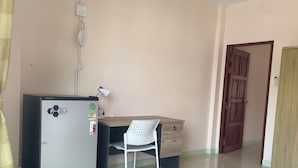 A room with a refrigerator, a desk, a chair, and a door. - Rawai cozy hostel (Rawai)