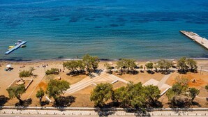 An aerial view of a beach with clear blue water, a pier, and trees. - Luxury Boutique Apartment • 5-Minute Walk to the Beach • Athens Riviera (Vouliagmeni)