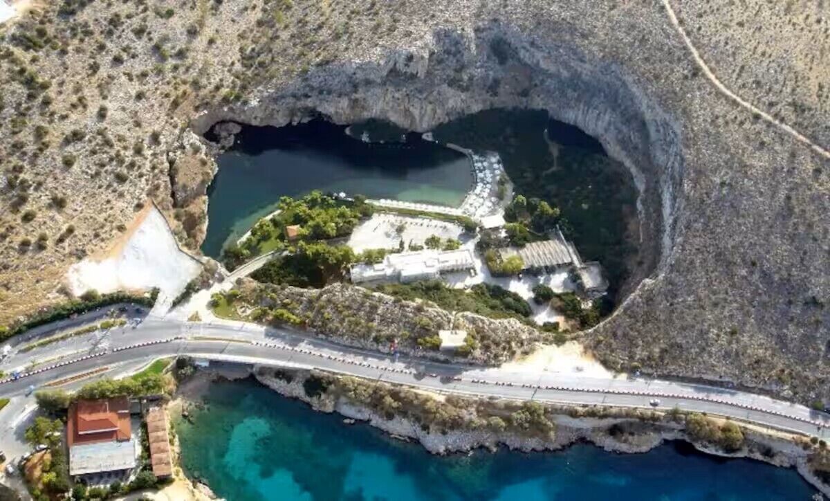Vue aérienne d’une zone côtière comprenant un vaste amphithéâtre naturel, une route et un petit ensemble de bâtiments.
