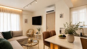 A modern living room with a sofa, a coffee table, and a dining area with chairs and a table. - Luxury Boutique Apartment • 5-Minute Walk to the Beach • Athens Riviera (Vouliagmeni)