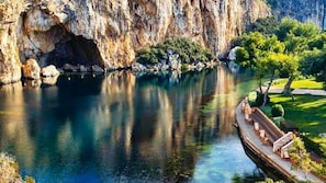 A river with a dock, rocky cliffs, and greenery. - Luxury Boutique Apartment • 5-Minute Walk to the Beach • Athens Riviera (Vouliagmeni)
