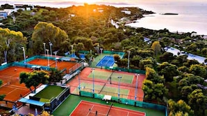 An aerial view of a tennis court complex surrounded by trees and a body of water. - Luxury Boutique Apartment • 5-Minute Walk to the Beach • Athens Riviera (Vouliagmeni)