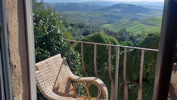 Una silla de mimbre en un balcón con vistas a un paisaje pintoresco.