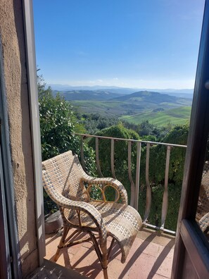 A wicker chair on a balcony overlooking a scenic landscape. - Authentische Toskana für Tierfreunde (Volterra)