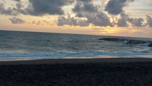 Una playa con olas, un promontorio rocoso y un cielo nublado.