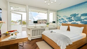 Ein modernes Schlafzimmer mit Bett, Schreibtisch und Blick auf die Stadt.