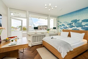 Ein modernes Schlafzimmer mit Bett, Schreibtisch und Blick auf die Stadt.