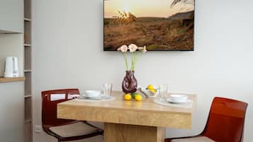 A dining table with a vase of flowers, two chairs, and a painting above.