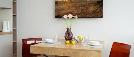 Una mesa de comedor con un florero, dos sillas y un cuadro en la pared.