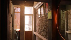 Un pasillo estrecho con una puerta de madera, un ventanal y una pared decorada con cuadros.