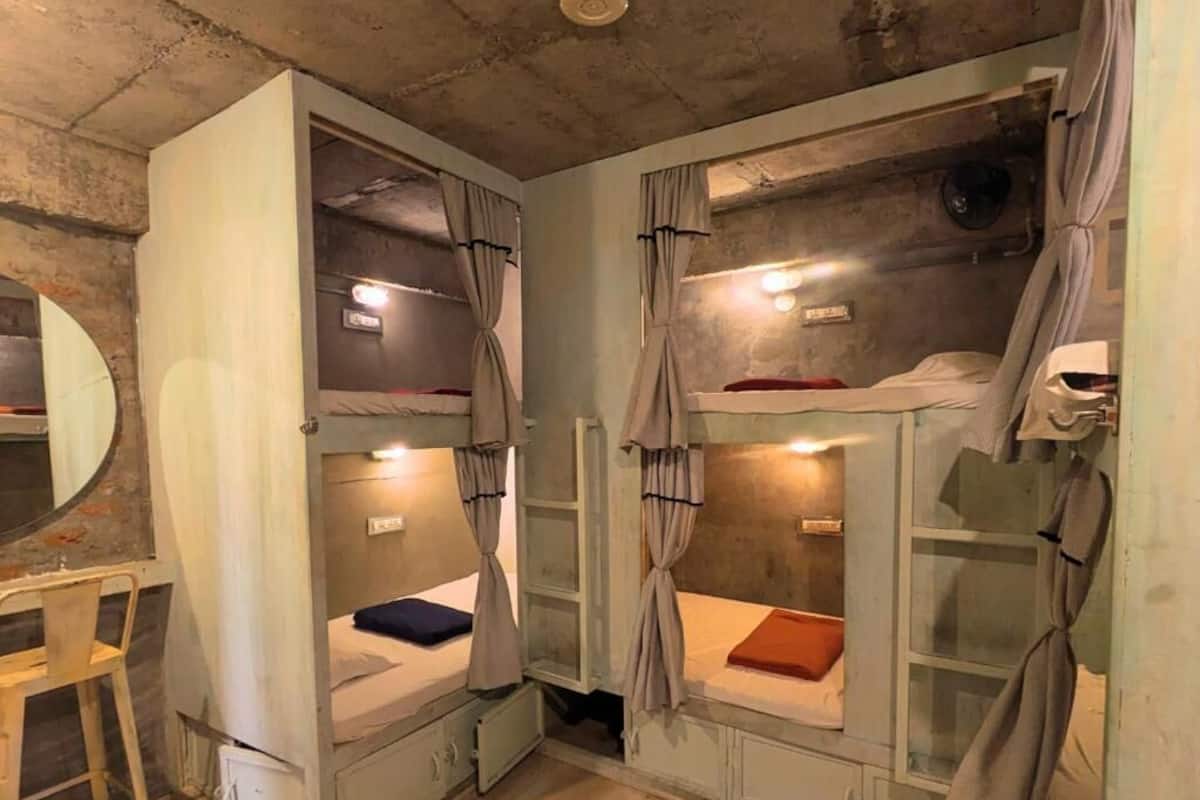 Quarto com beliches, escrivaninha e espelho.