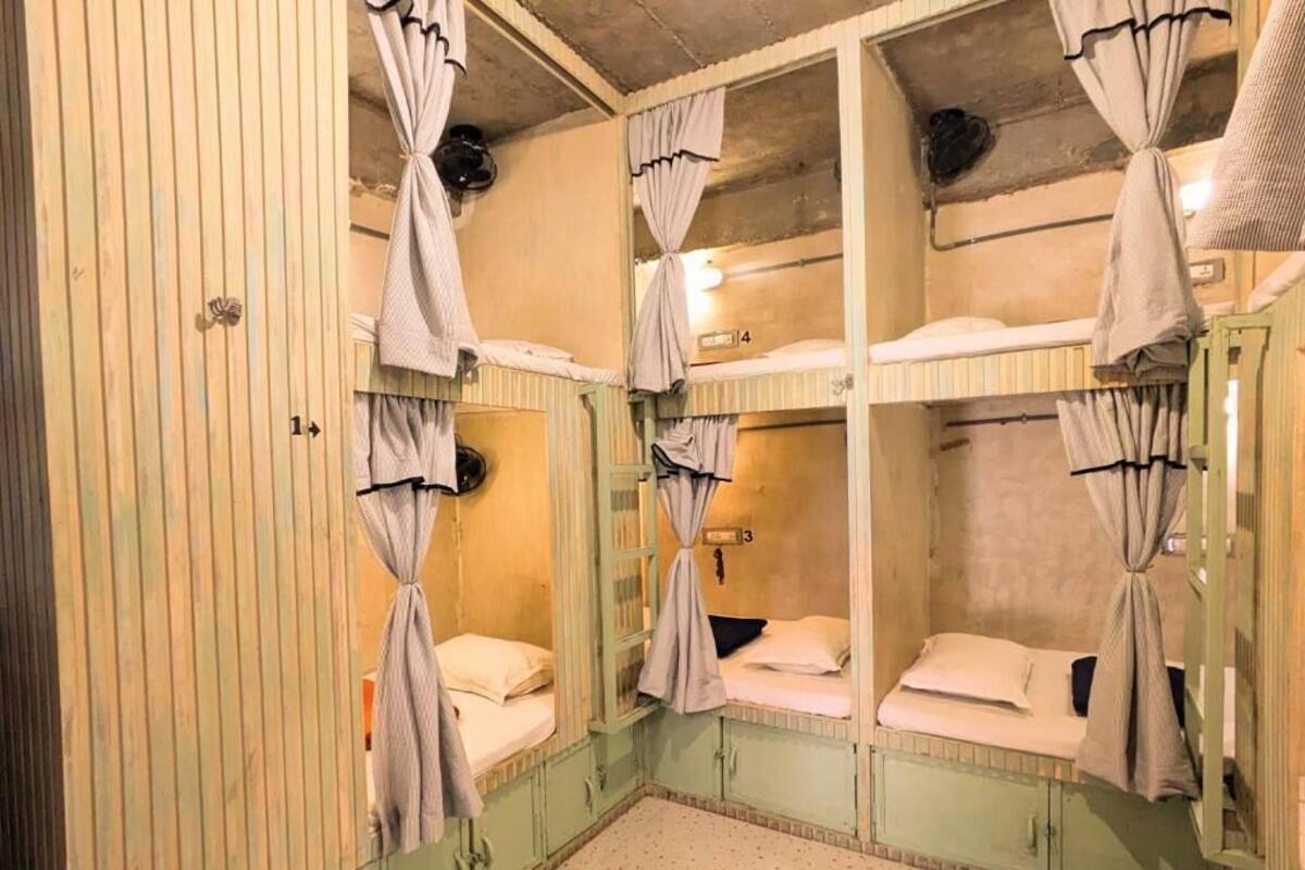Quarto com beliches, guarda-roupa de madeira e cortinas.