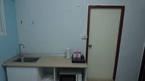A small kitchenette with a sink, microwave, and a shelf with bottled water and a cup. - Happy Residences Pattaya 2 (Pattaya)