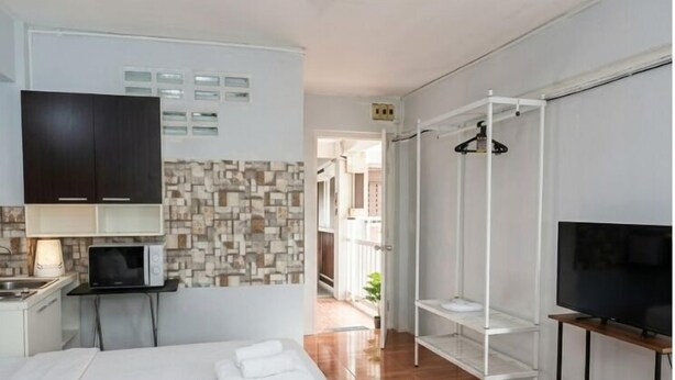 A hotel room with a bed, a TV, a small desk with a lamp, a wardrobe, and a bathroom with a shower and a toilet. - Happy Residences Pattaya 2 (Pattaya)