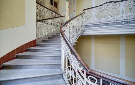 A staircase with ornate white railings and a wooden handrail, leading to an upper floor.