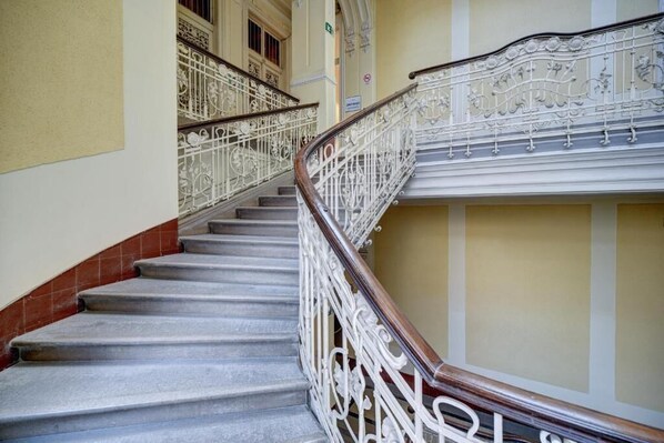 A staircase with ornate white railings and a wooden handrail, leading to an upper floor.
