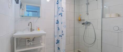 A bathroom with a glass shower enclosure, a white sink with a mirror above it, and a toilet with a towel on it.
