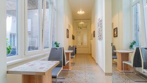 A corridor with seating areas, patterned floor tiles, and large windows.